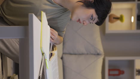 Vertical-video-of-Female-student-trying-to-finish-her-homework-at-night.